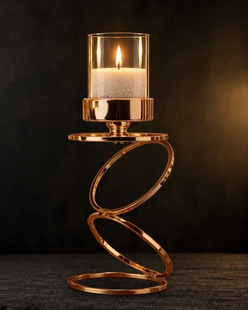 A gold rings candle holder with a glass chimney and a lit candle